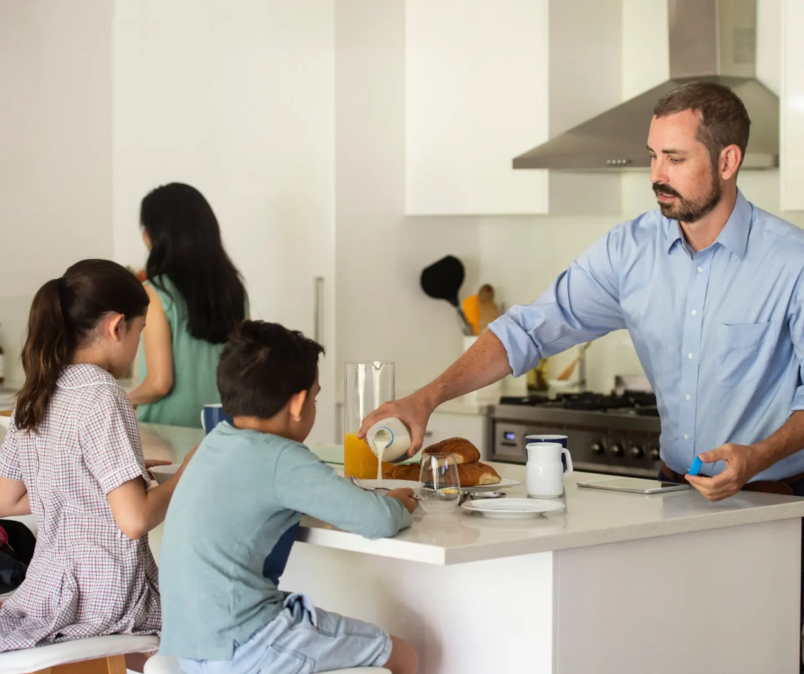Foster carers making breakfast for two foster children before school.