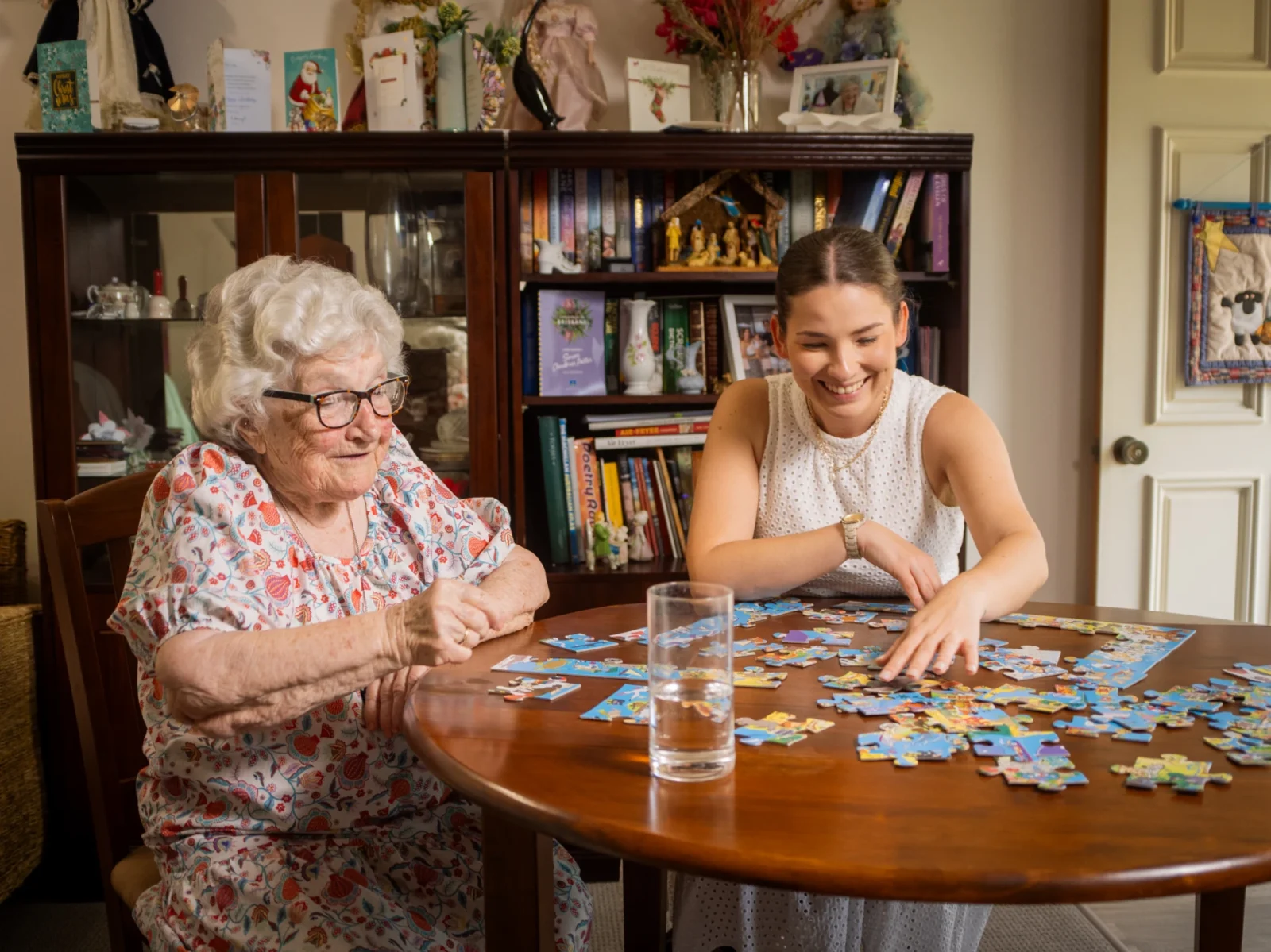 Young woman volunteering her time to help older client with a puzzle.