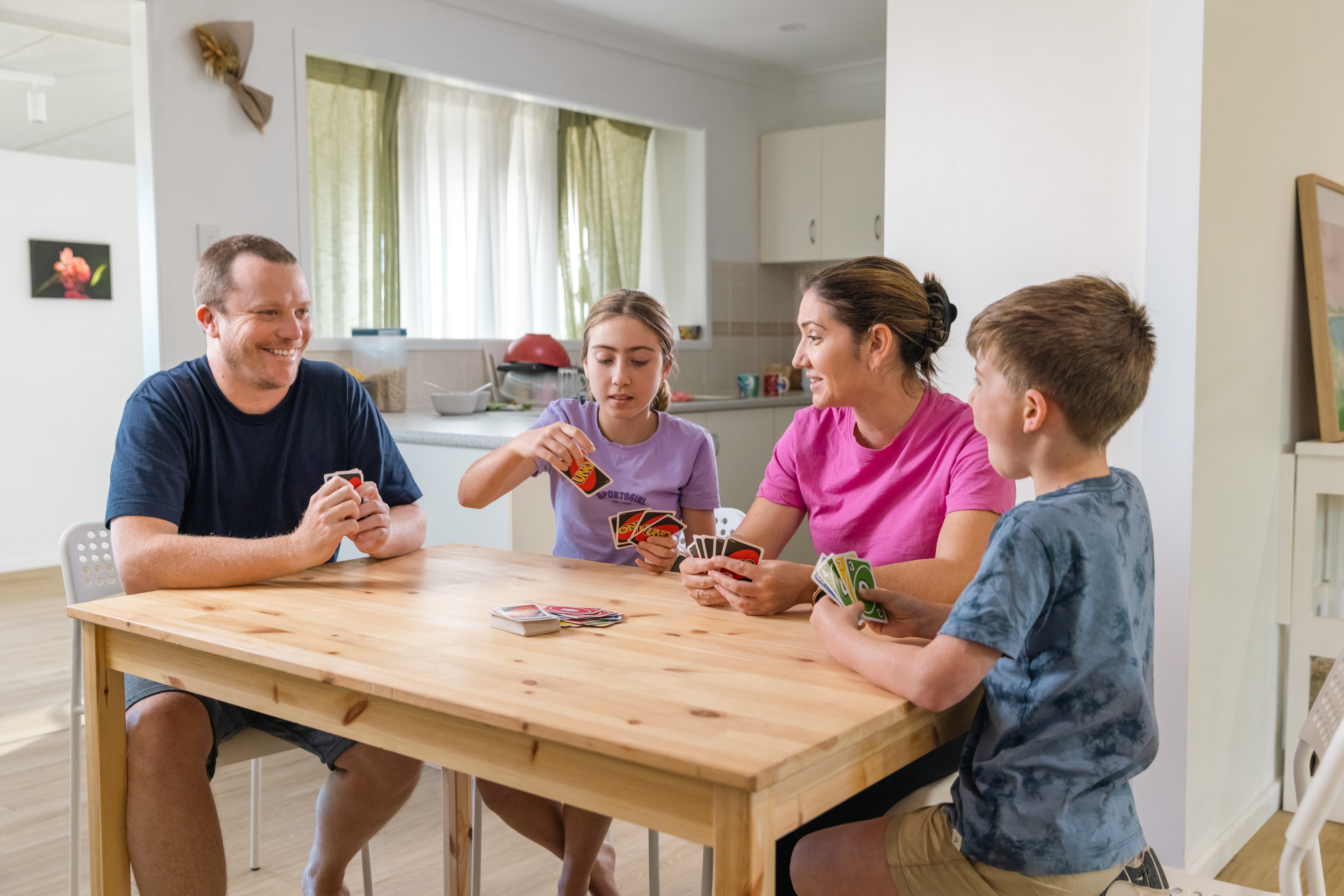 Free activities to do with your kids: family of four playing Uno at the kitchen table