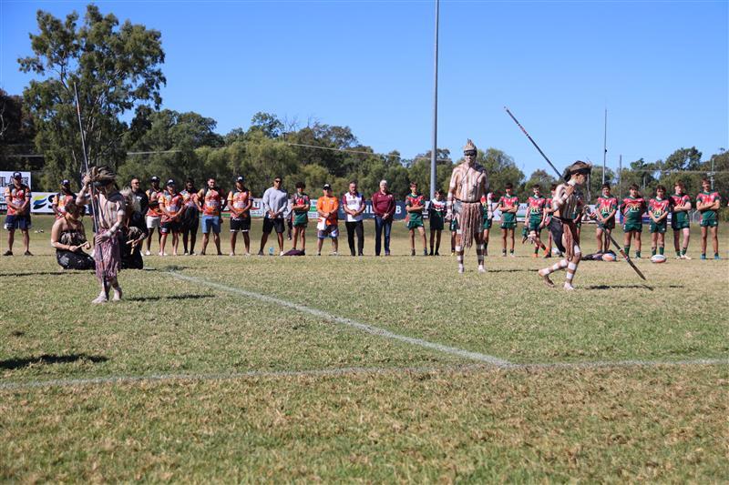 Ceremony with a group of First Nations people on a football field.
