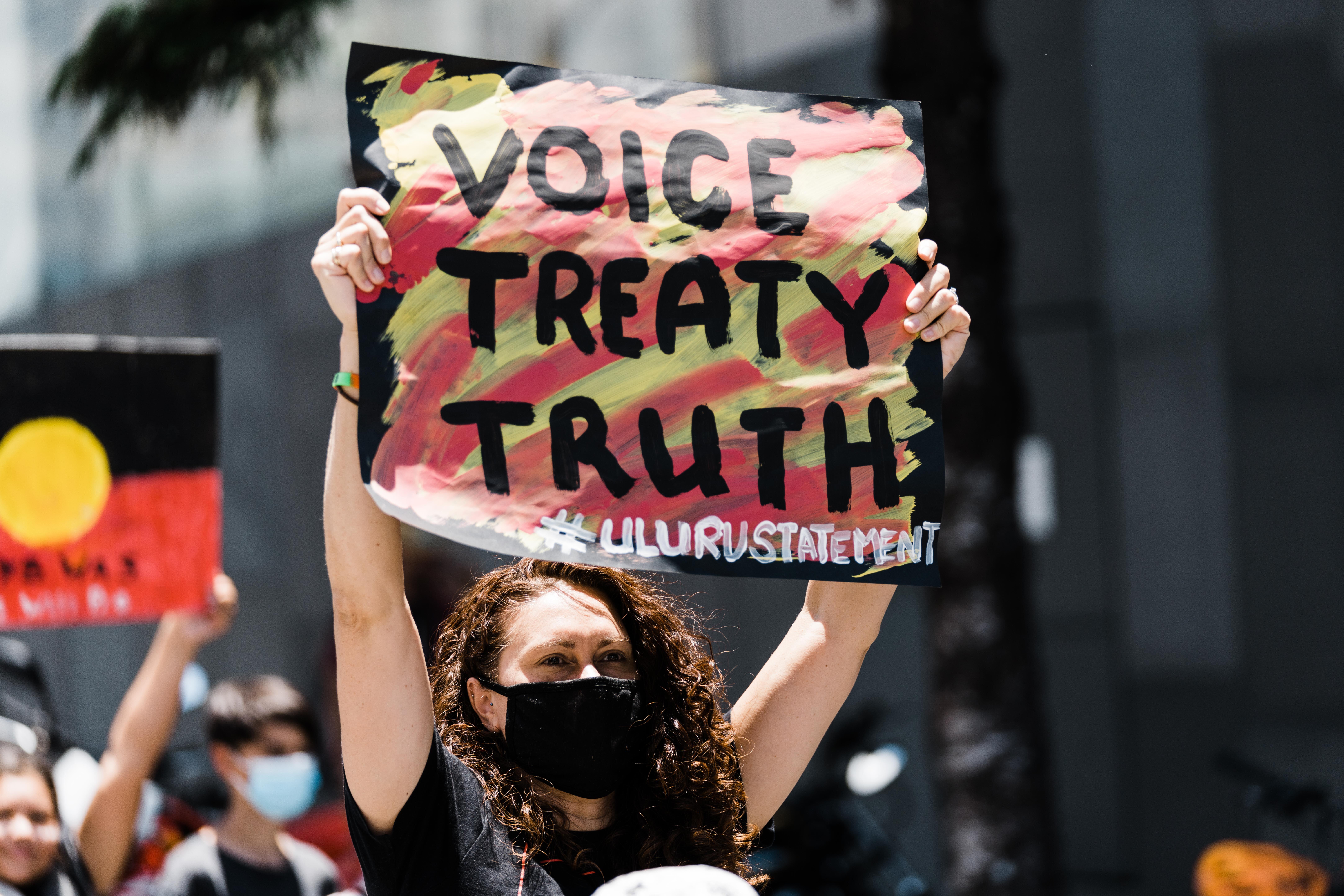 Person holding up a sign saying: Voice, Treaty Truth #ulurustatement