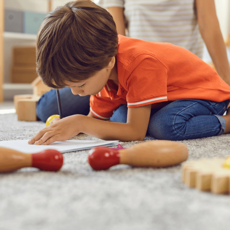 Foster child sitting on the floor drawing a picture