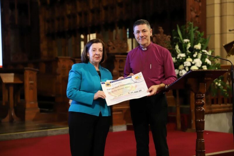 Anglicare Southern Queensland’s Chair of the Community Services Commission, Tracy Morgan, and Archbishop Jeremy Greaves holding a St John’s Cathedral cheque for $25,000 for Anglicare’s Youth Homelessness Accommodation Project at the Loaves and Fishes luncheon fundraiser, which was held in the cathedral on Tuesday, 3 June 2025