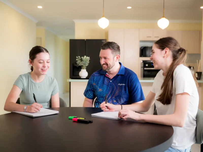 Out-of-home care practitioner helping 2 young girls with homework
