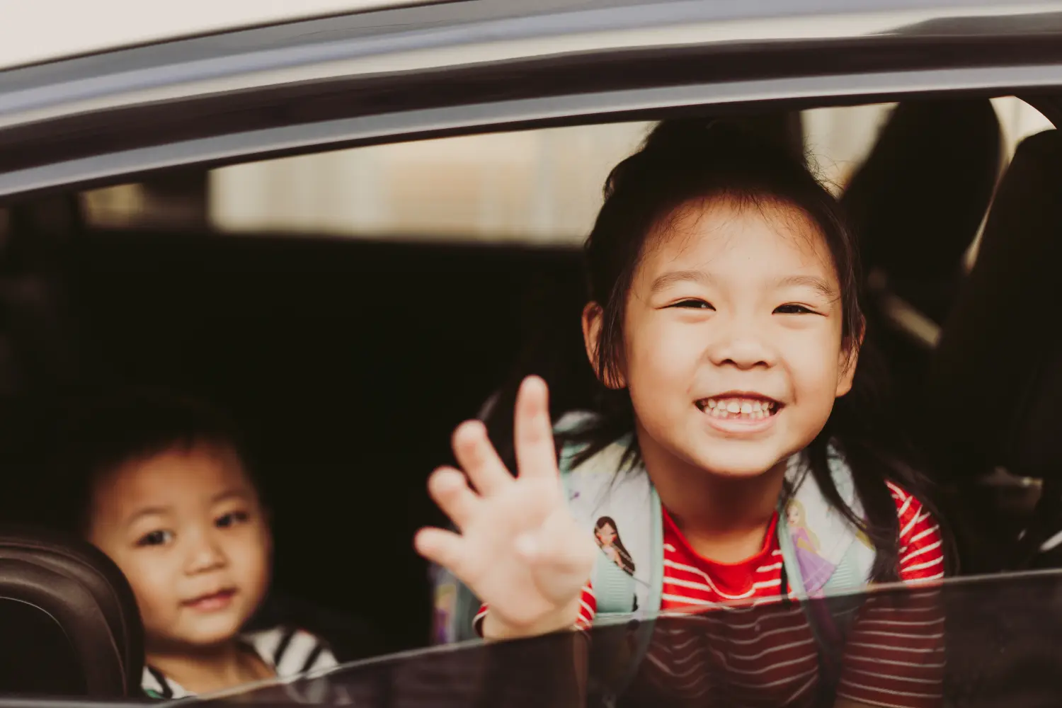 Children sitting in the back seat of a car during a trip, representing positive experiences provided through respite foster care.