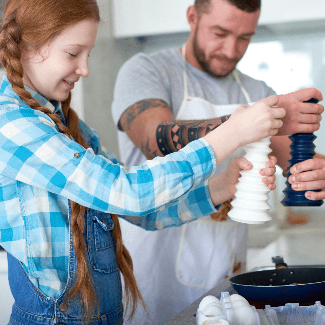 Foster parent of adolescents. Foster dad cooking with teen daughter.