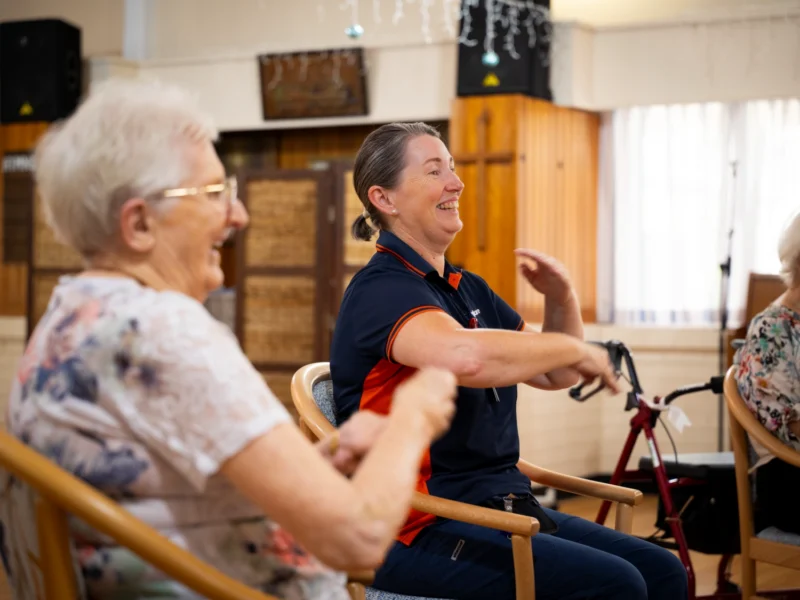Seniors participating in a group activity with a respite carer in a community setting during respite care.