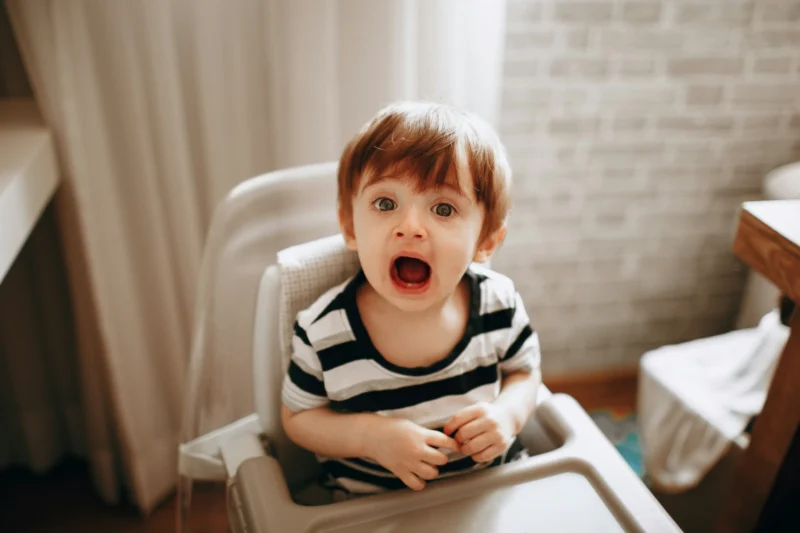 Toddler in a high chair showing strong emotion, illustrating building resilience in children.