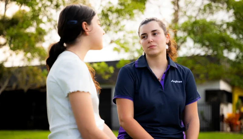 Youth worker sitting on a park bench with young female client.