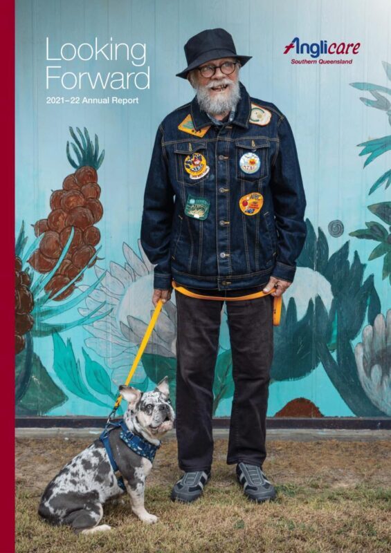 Old man in jacket with colourful badges standing with dog on lead