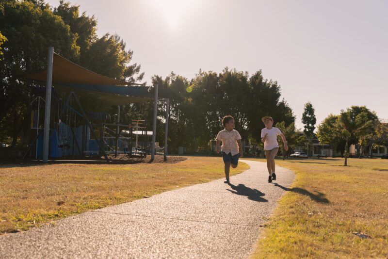 Two young boys running down a path in a park