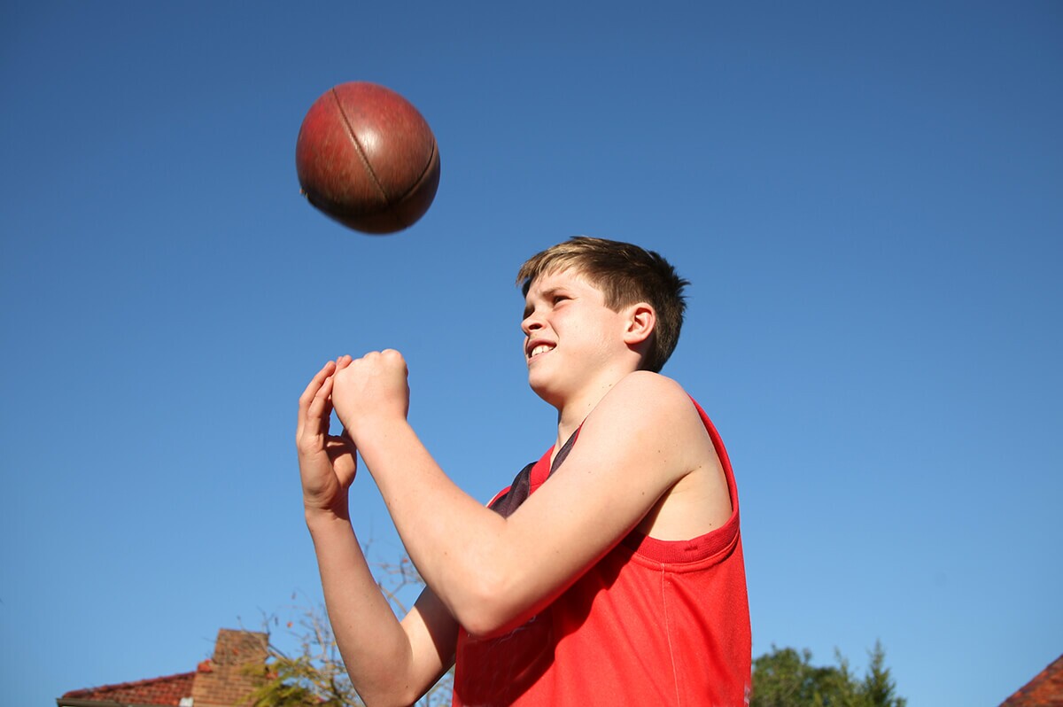 Alan's foster care story: You boy playing with an Australian Rules football
