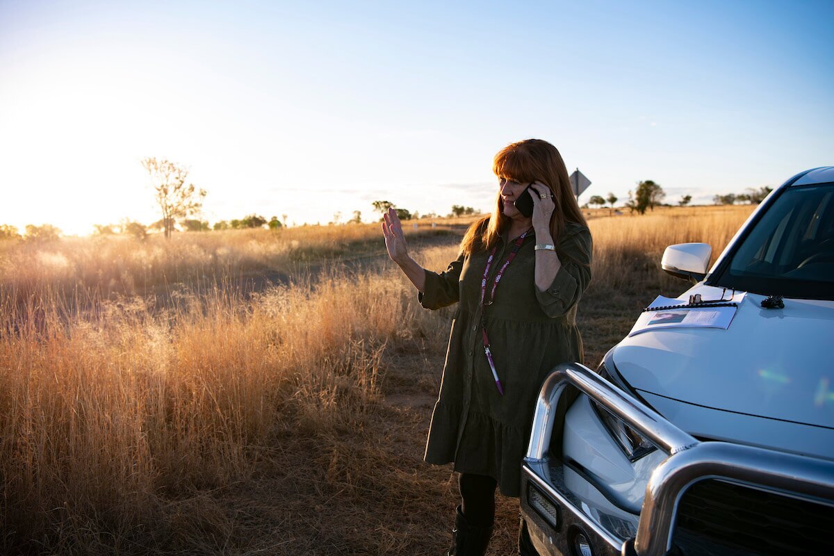 Person outside, standing next to car while talking on the phone