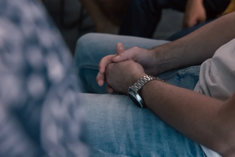 Man holding his hands and sitting in a counselling program.