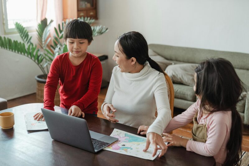 Parent with children, working on computer at home.