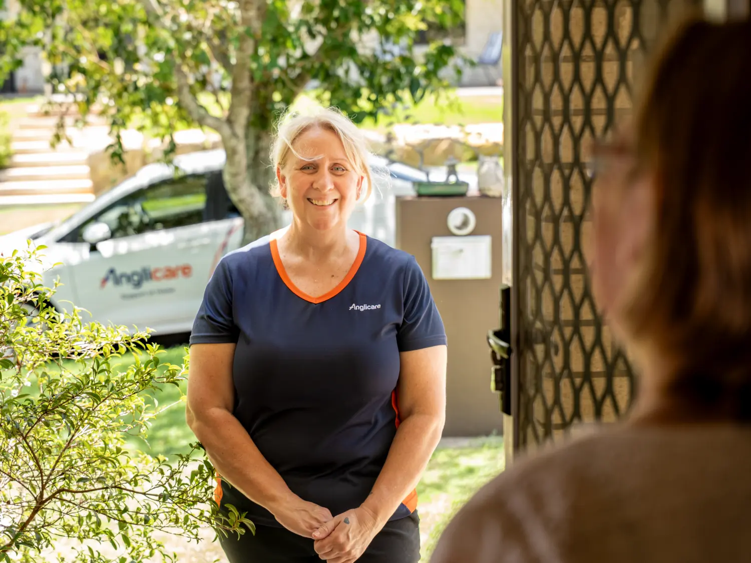 Anglicare staff worker smiling at female client outside her home