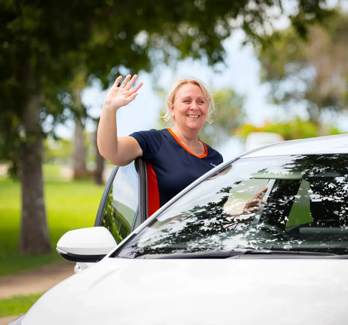 Anglicare worker arriving at a client's house and waving at them from the footpath.