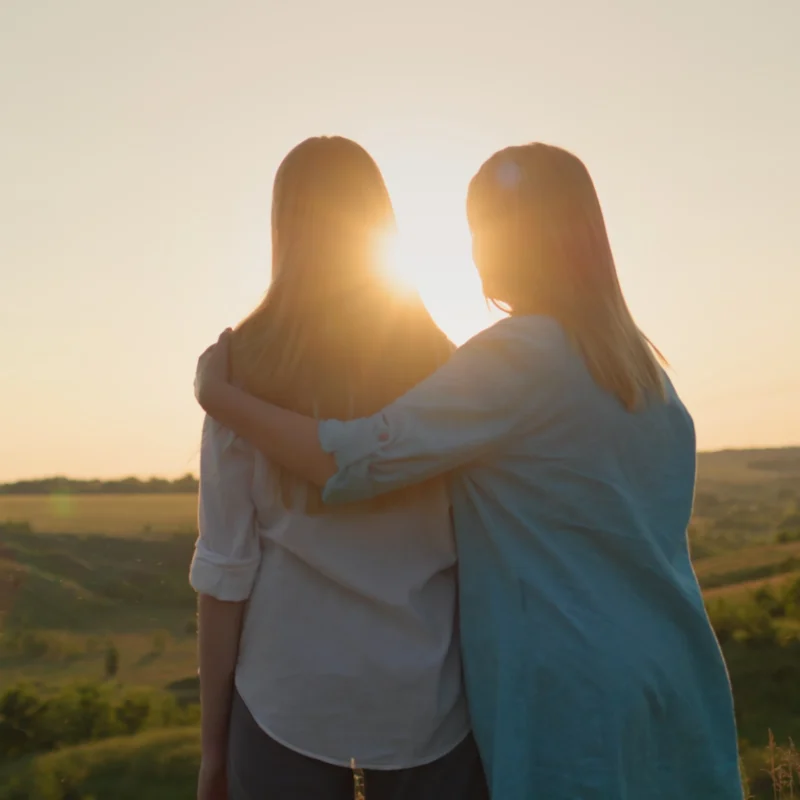 Youth justice program female client hugging her mother while looking at sunset.