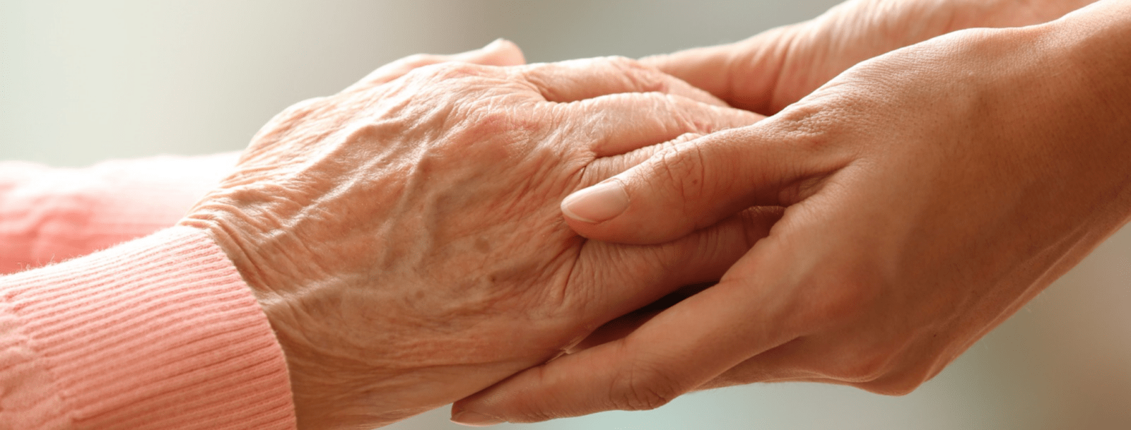 Carer compassionately holding loved ones hand