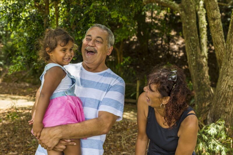 First Nations foster carers standing in the garden with young girl.