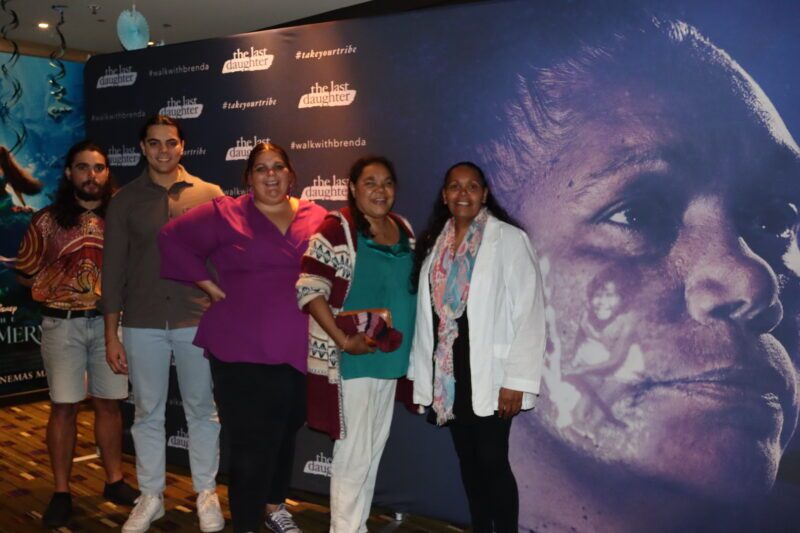 Anglicare staff pictured in front of poster for The Last Daughter movie premiere 