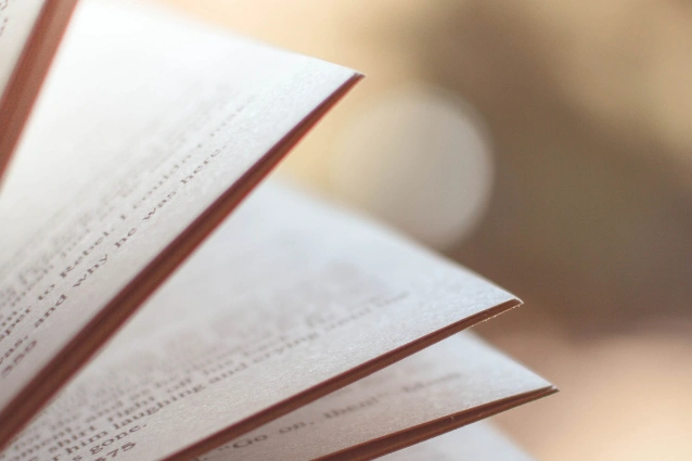 Close-up of the edges of several pages in an open book, with text visible but out of focus. The background is blurred, highlighting the soft texture of Research and Advocacy Publications' carefully crafted paper.
