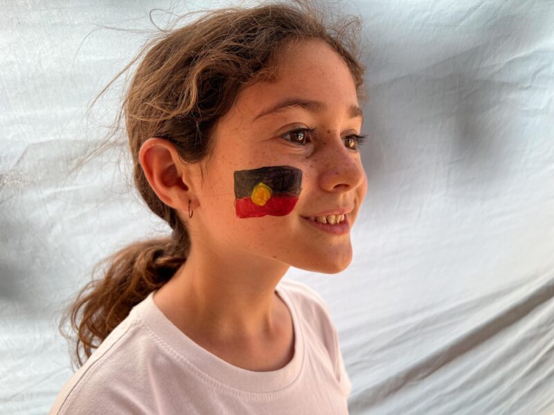 Child with Aboriginal flag face painting on Reconciliation Week
